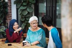 three people sitting at a table chatting and laughing